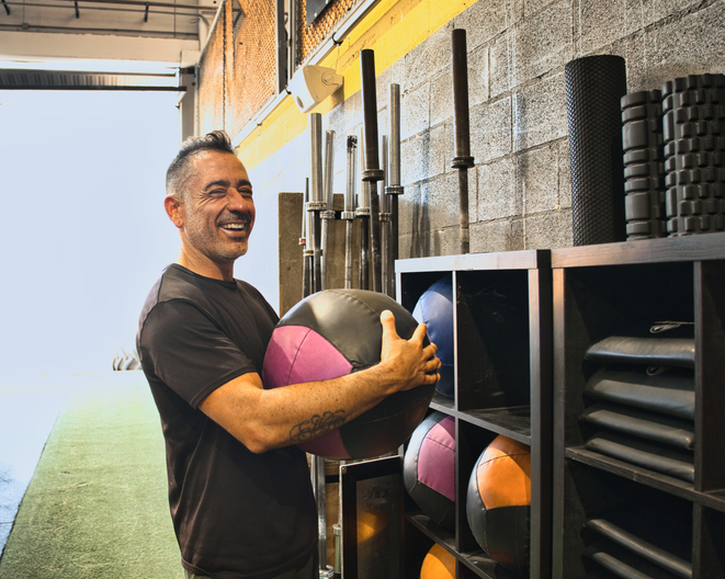 Smiling man holding a medicine ball in gym gym