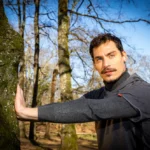 Runner is doing stretching in the woods.